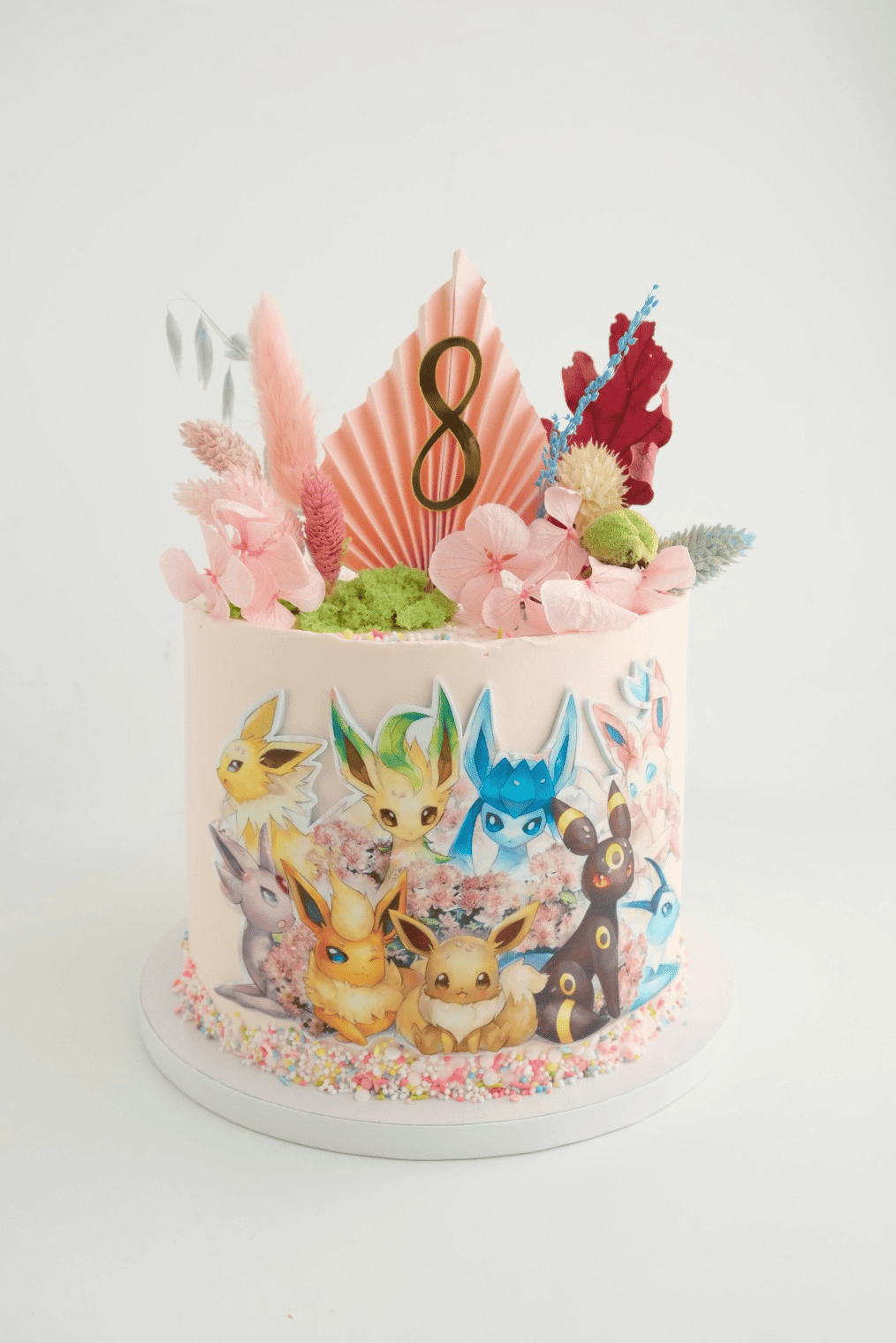Un pastel con una imagen de Eevee y flores.