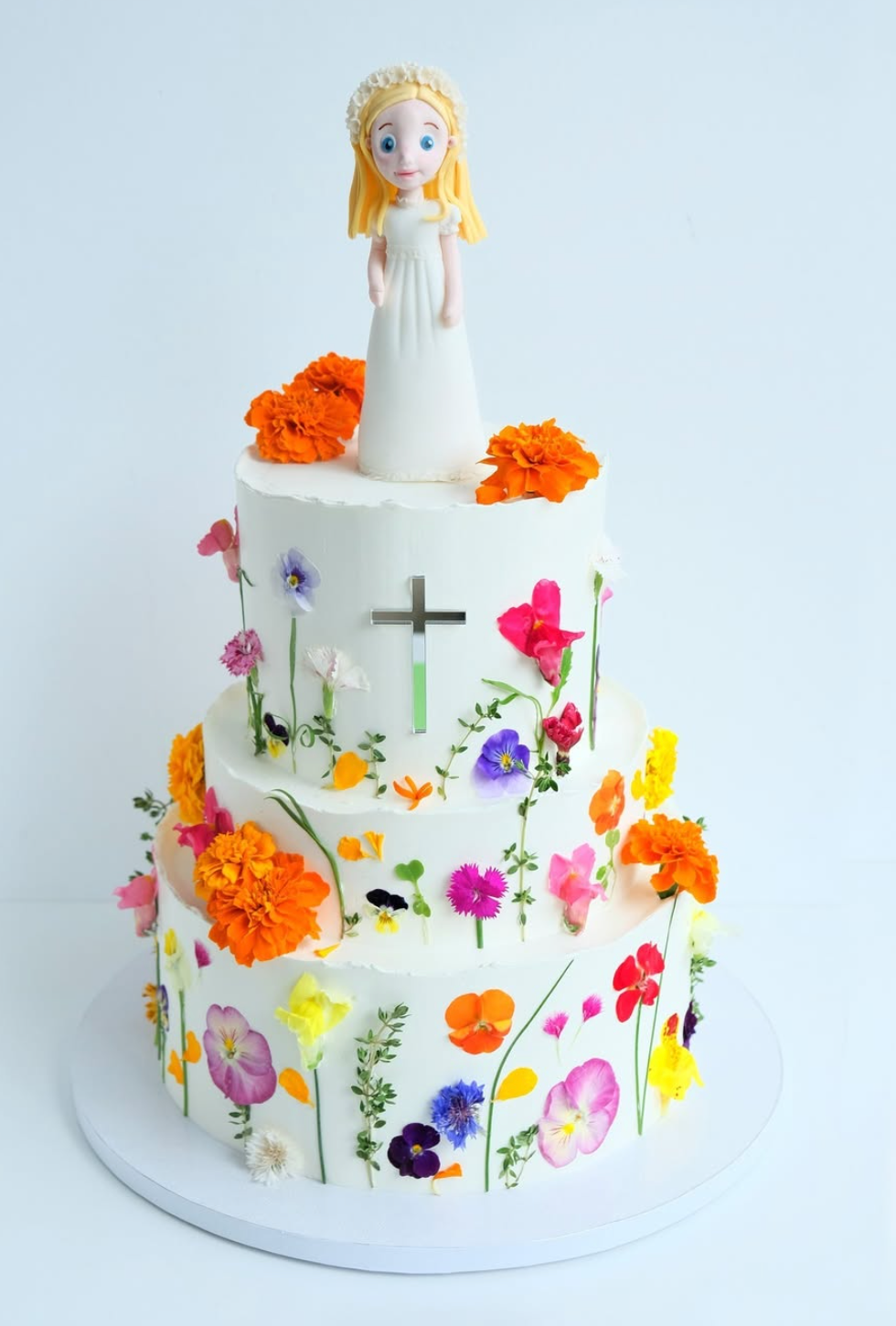 Un pastel con flores y una muñeca encima.