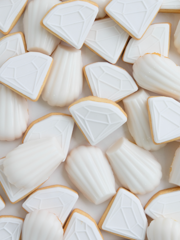 Un montón de galletas blancas con forma de diamantes y conchas.