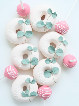 Donas blancas con bombones rosados y hojas verdes