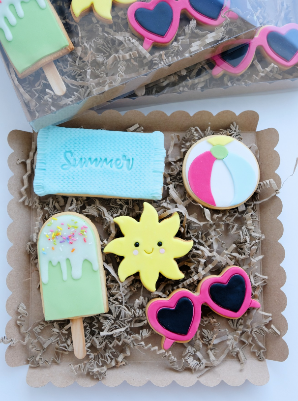 Una caja de galletas con temática de verano con una pelota de playa y gafas de sol.