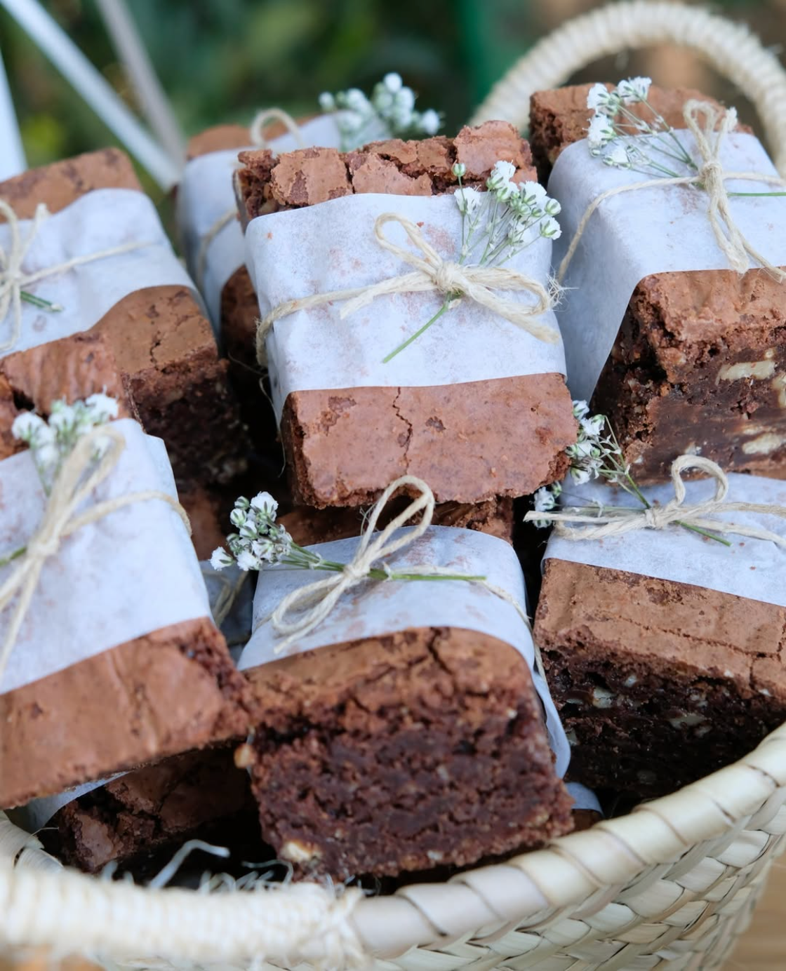 Una canasta llena de brownies envueltos en papel encerado y atados con cordel