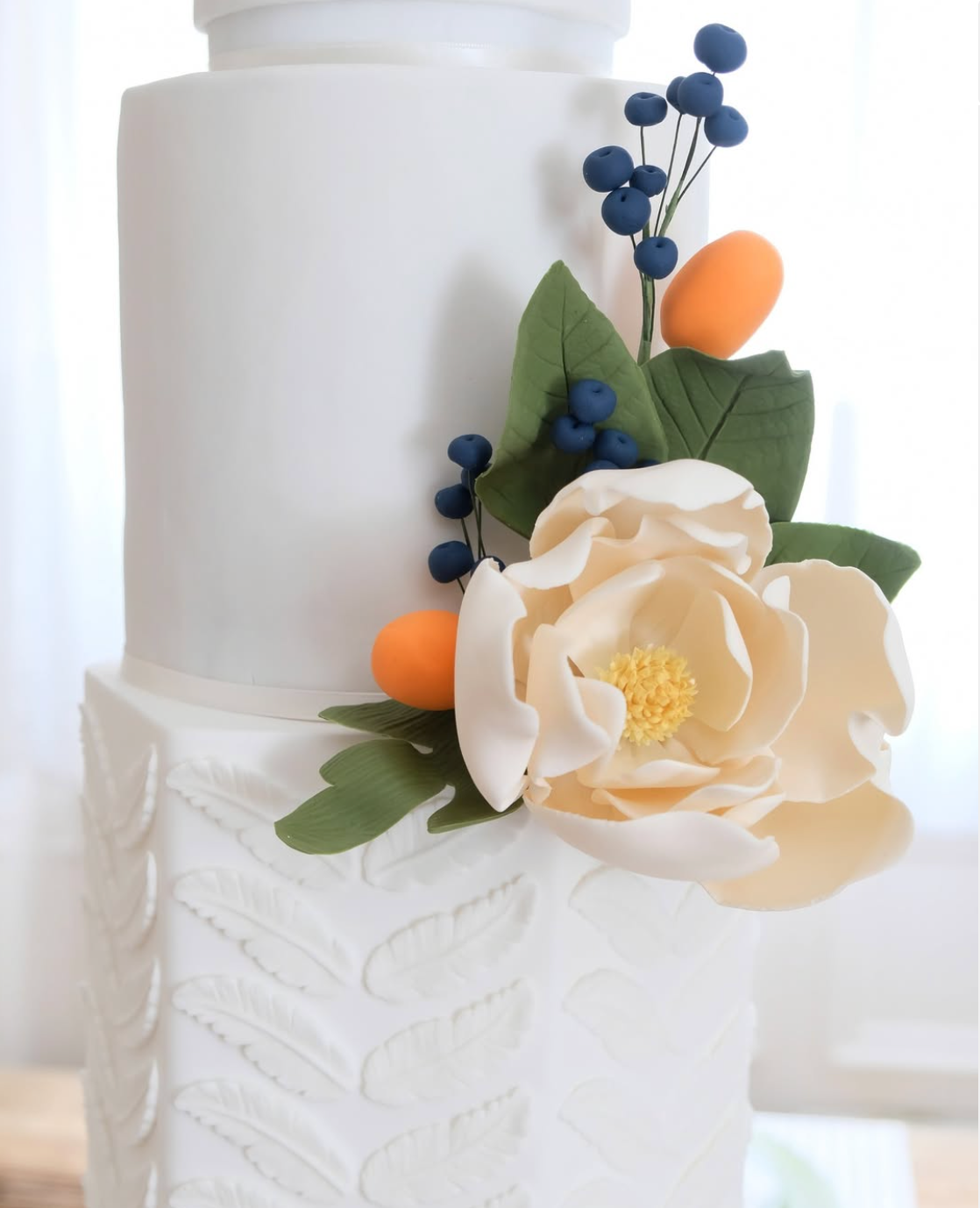 Un pastel blanco con flores y bayas encima.