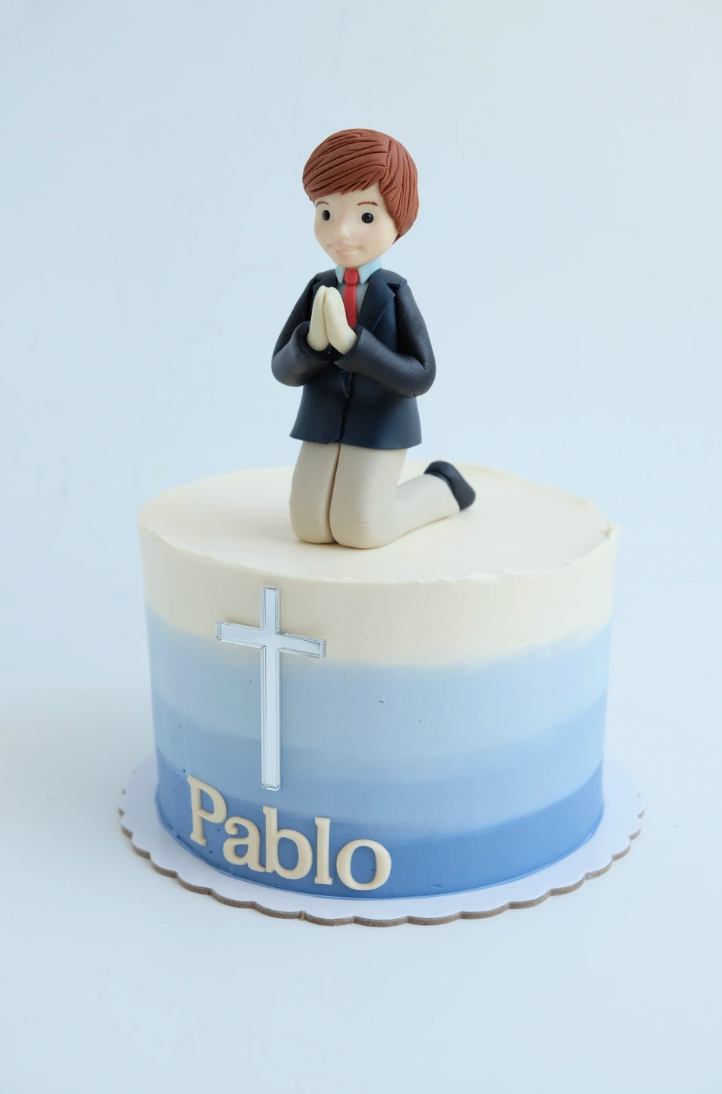 Un pastel con un niño rezando encima. de nombre pablo
