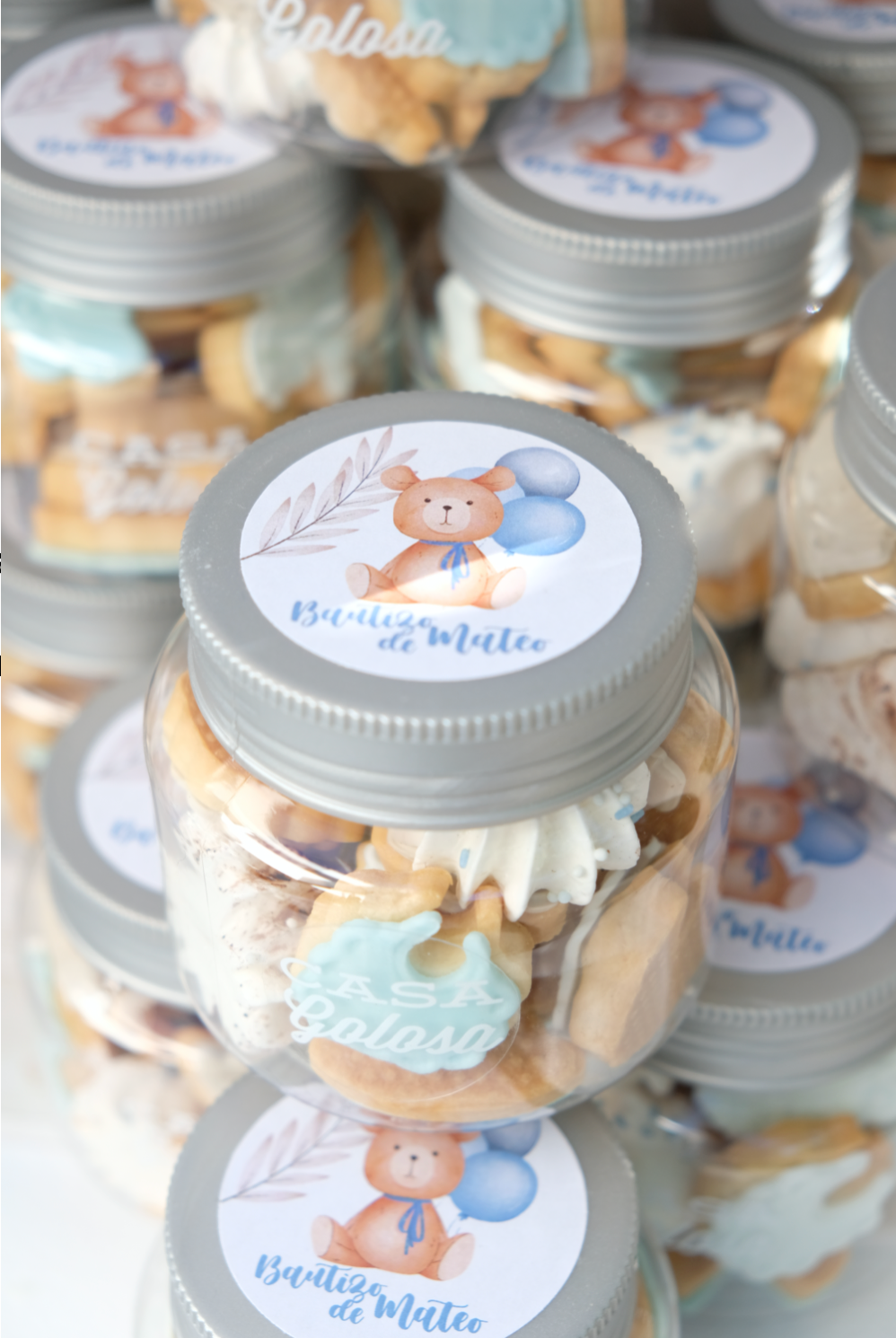 Una pila de frascos llenos de galletas y un osito de peluche.