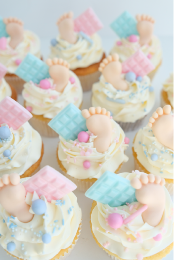 Un montón de cupcakes con pies de bebé para un baby shower.