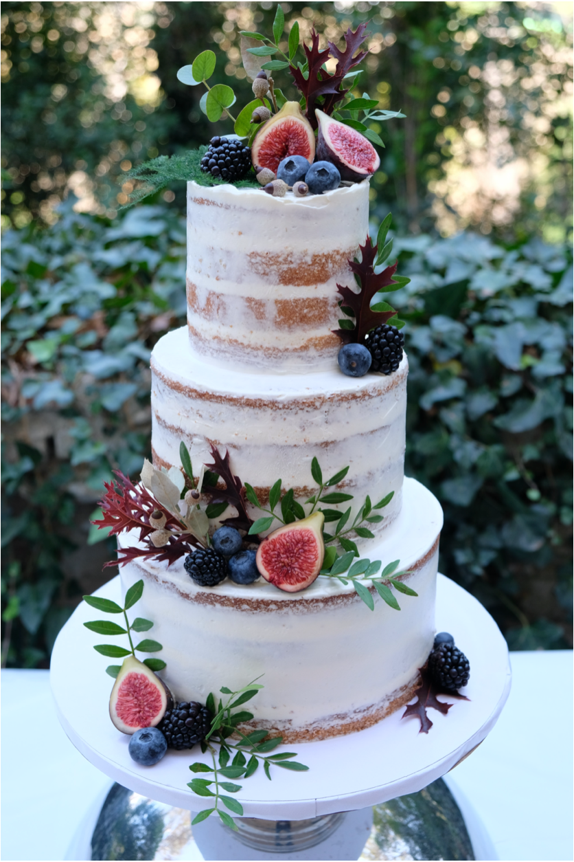 Pastel blanco de 3 pisos con frutos y hojas verdes