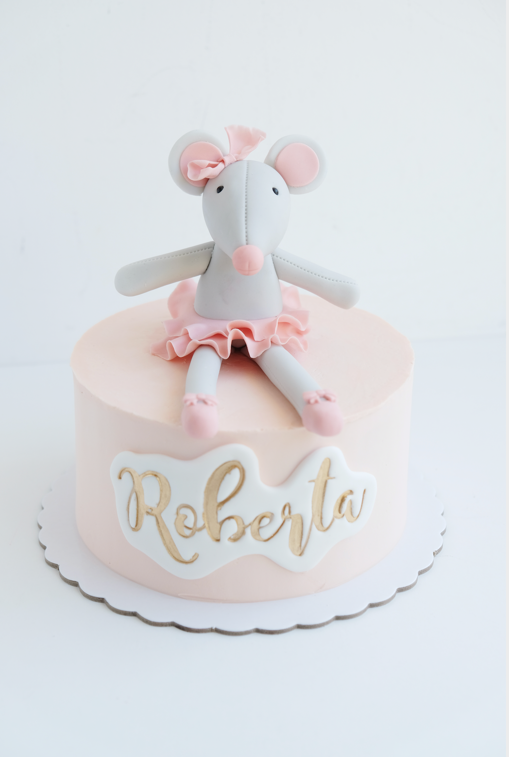 Un pastel rosa con un ratón de peluche encima y el nombre Roberta.