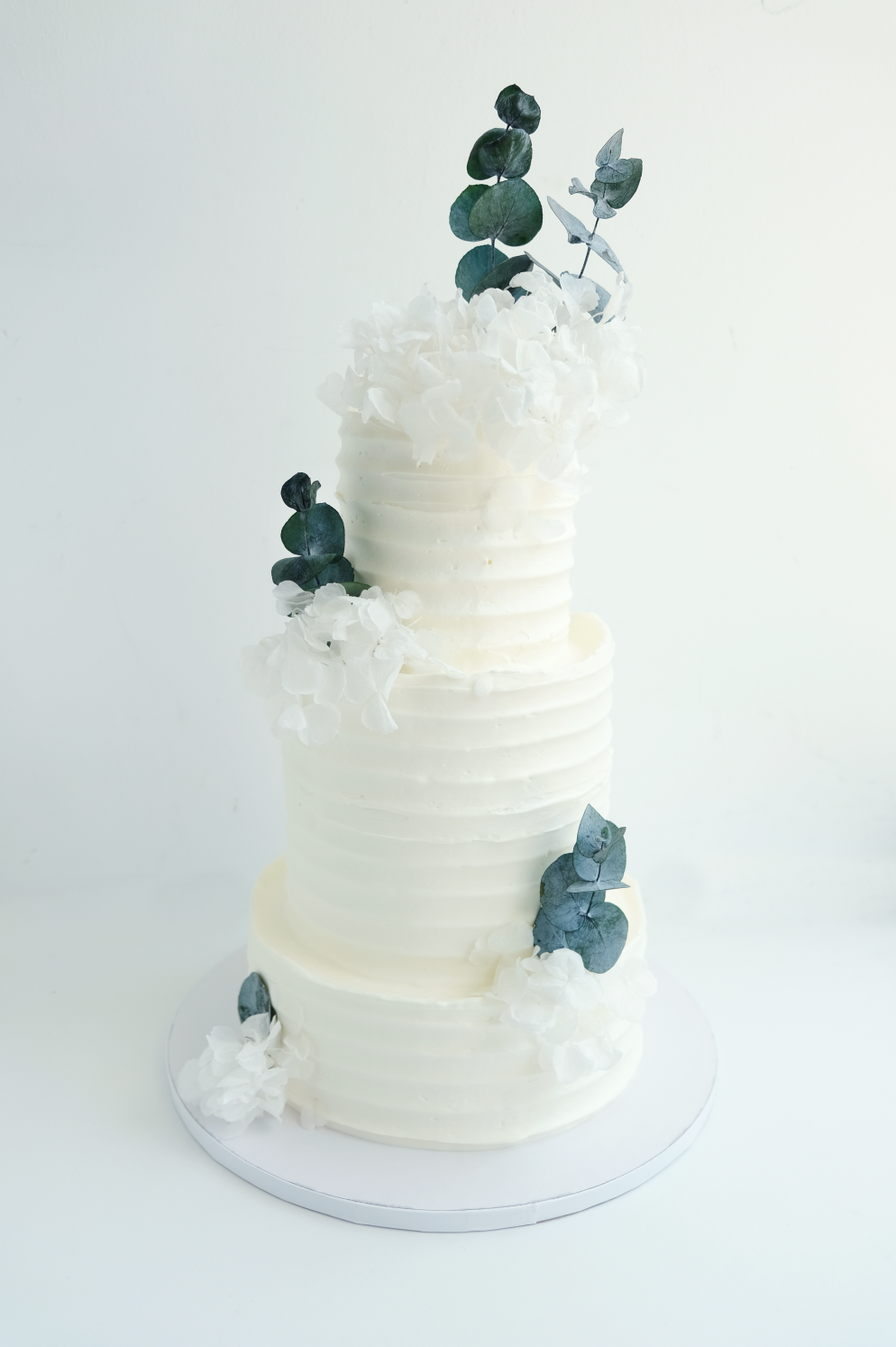 Un pastel de bodas blanco con flores azules encima.