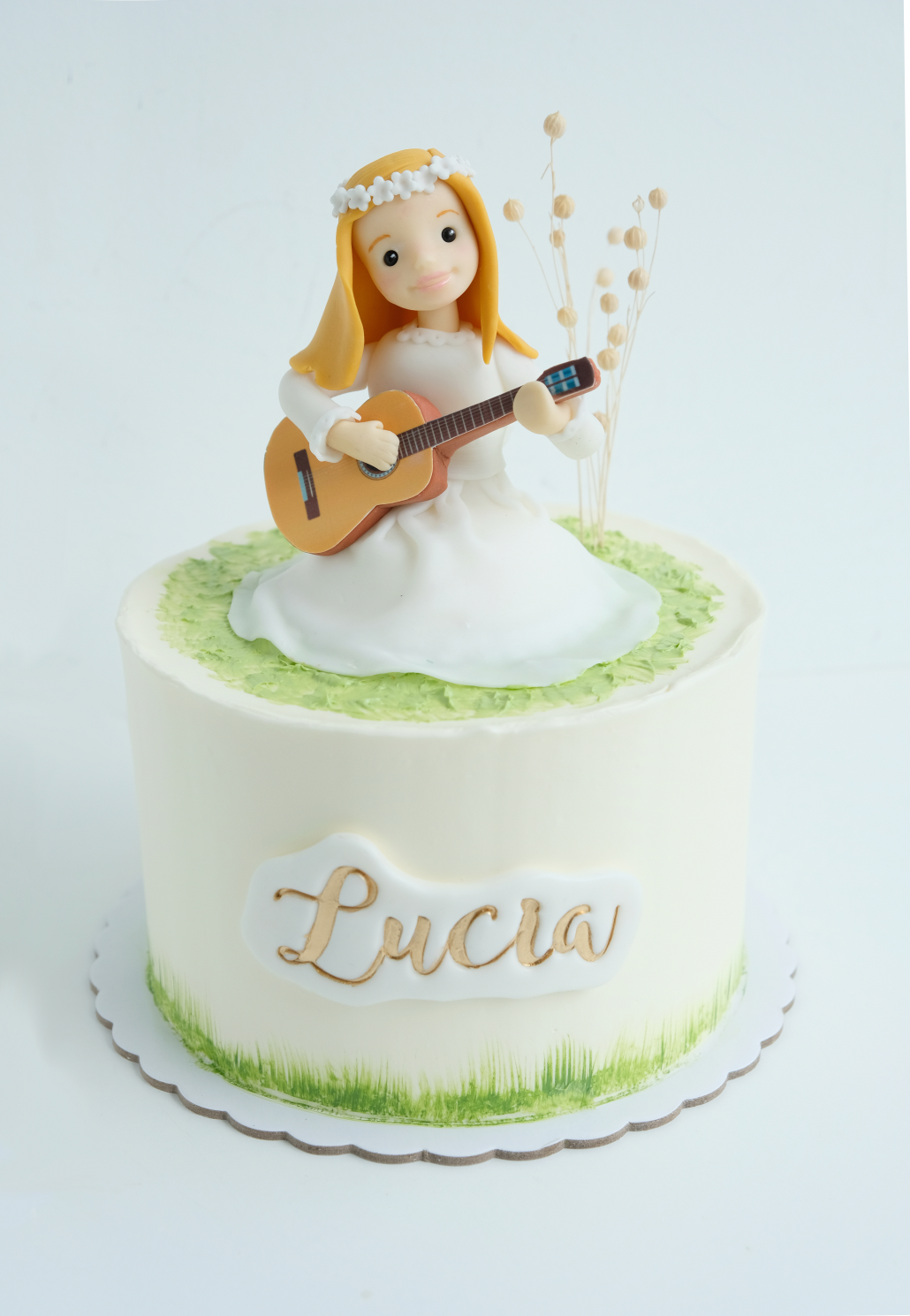 Un pastel con una figura de una niña sosteniendo una guitarra. de nombre lucia