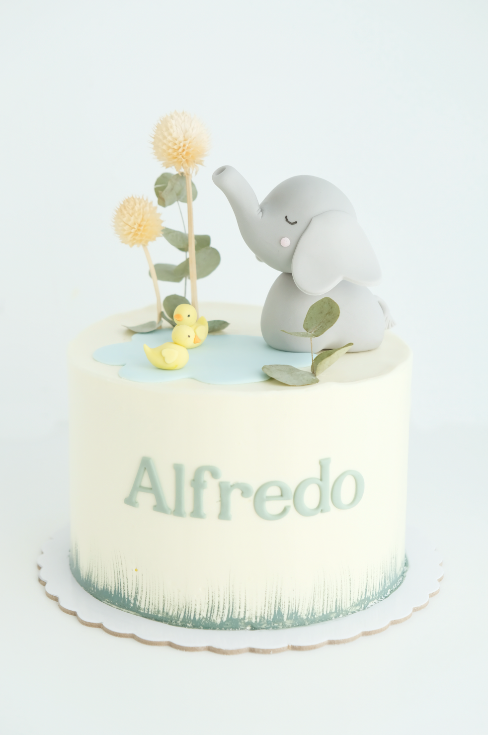 Un pastel con un elefante encima y el nombre Alfredo.