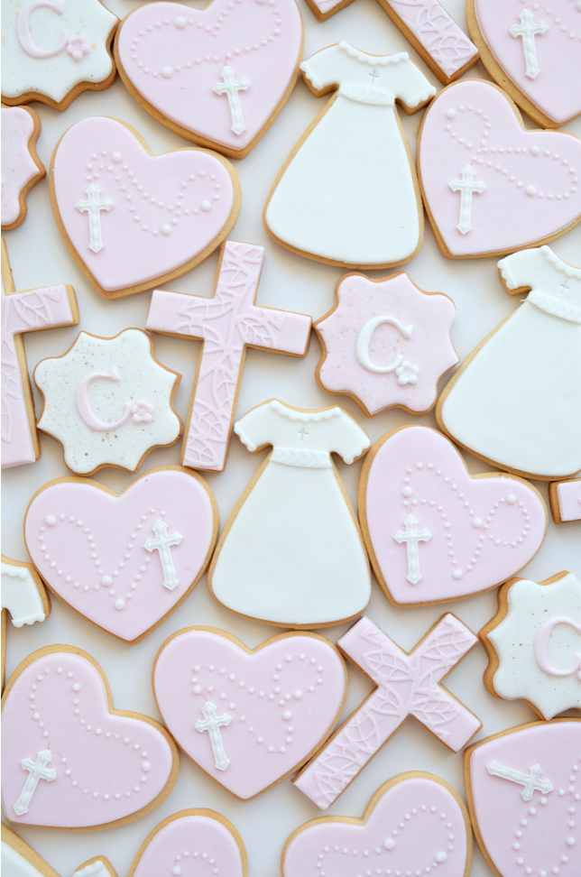 Un montón de galletas rosas y blancas con cruces y corazones en ellas.