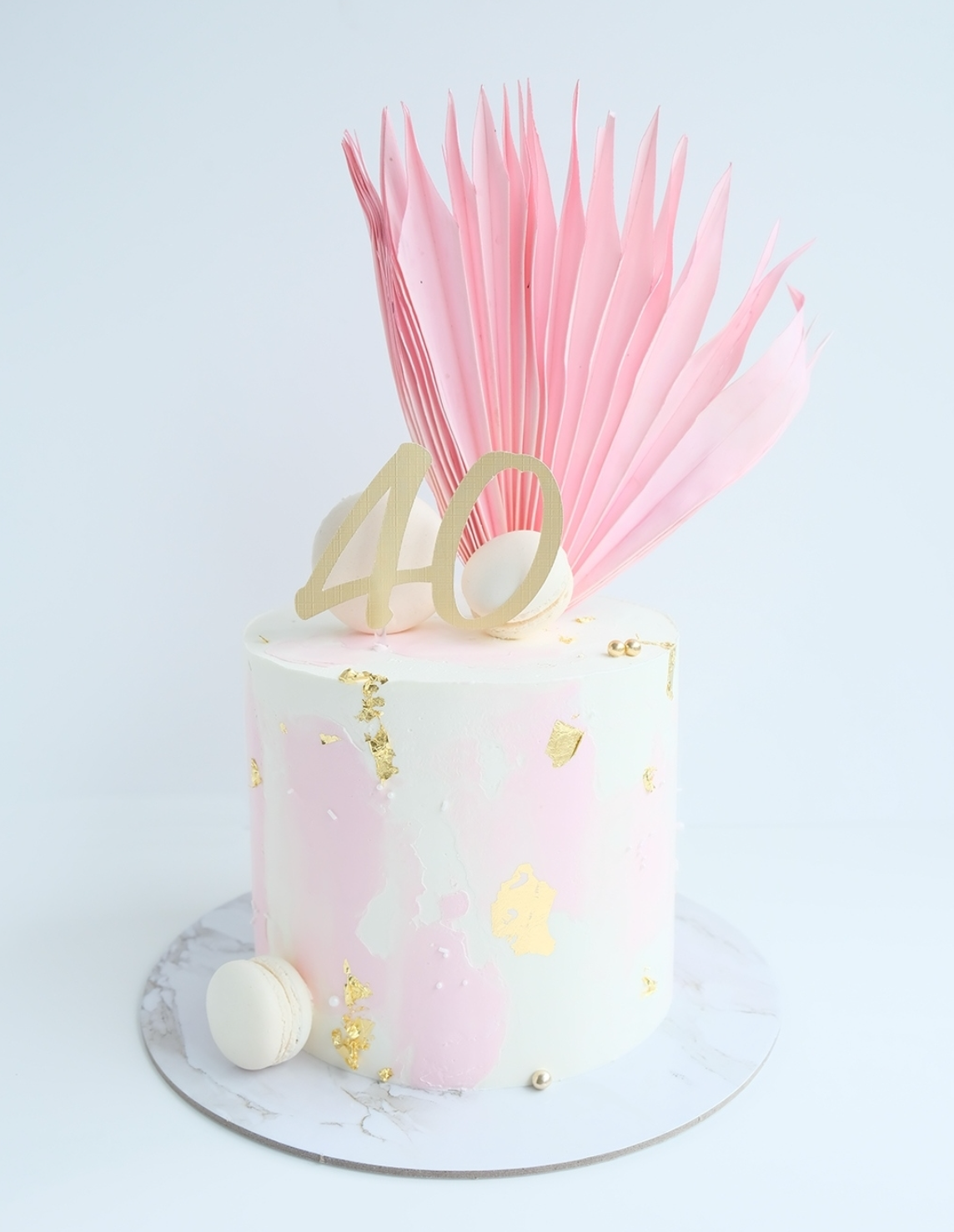 Un pastel rosa y blanco con un número 40 dorado encima.