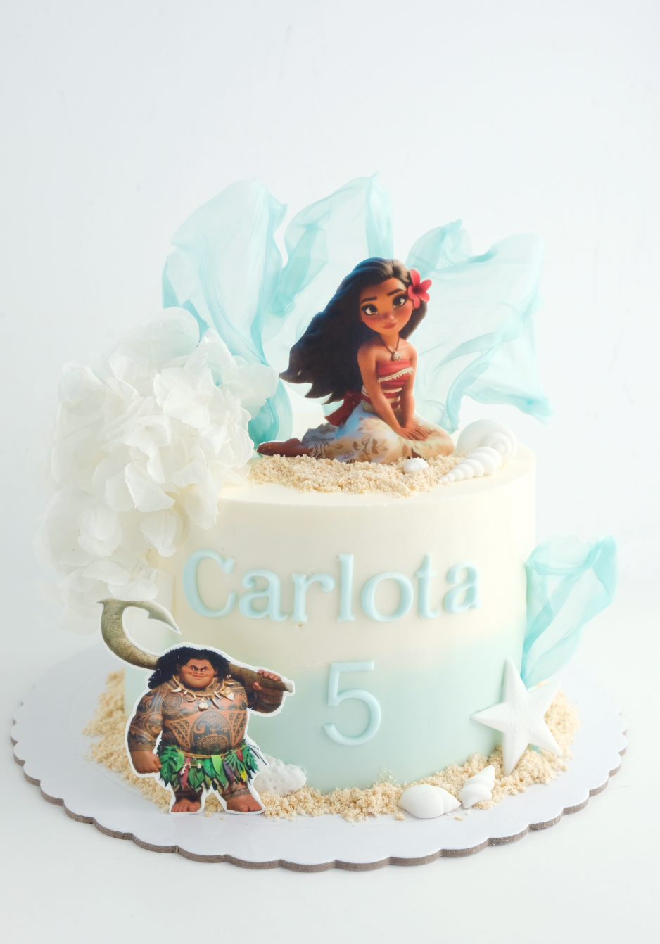 Un pastel de cumpleaños para una niña con Moana y Maui en él.