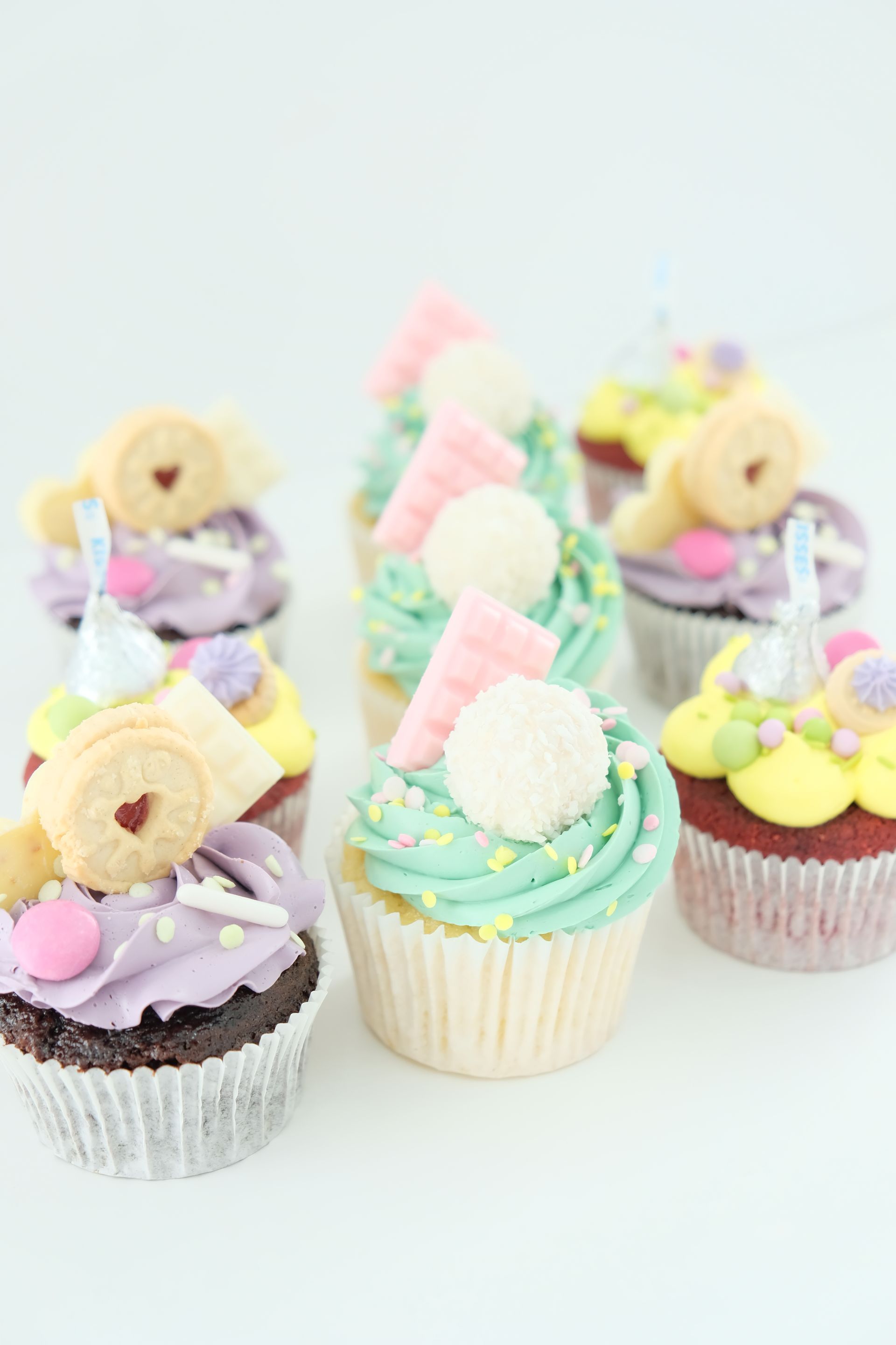 Un montón de cupcakes con diferentes aderezos encima están sobre una mesa.