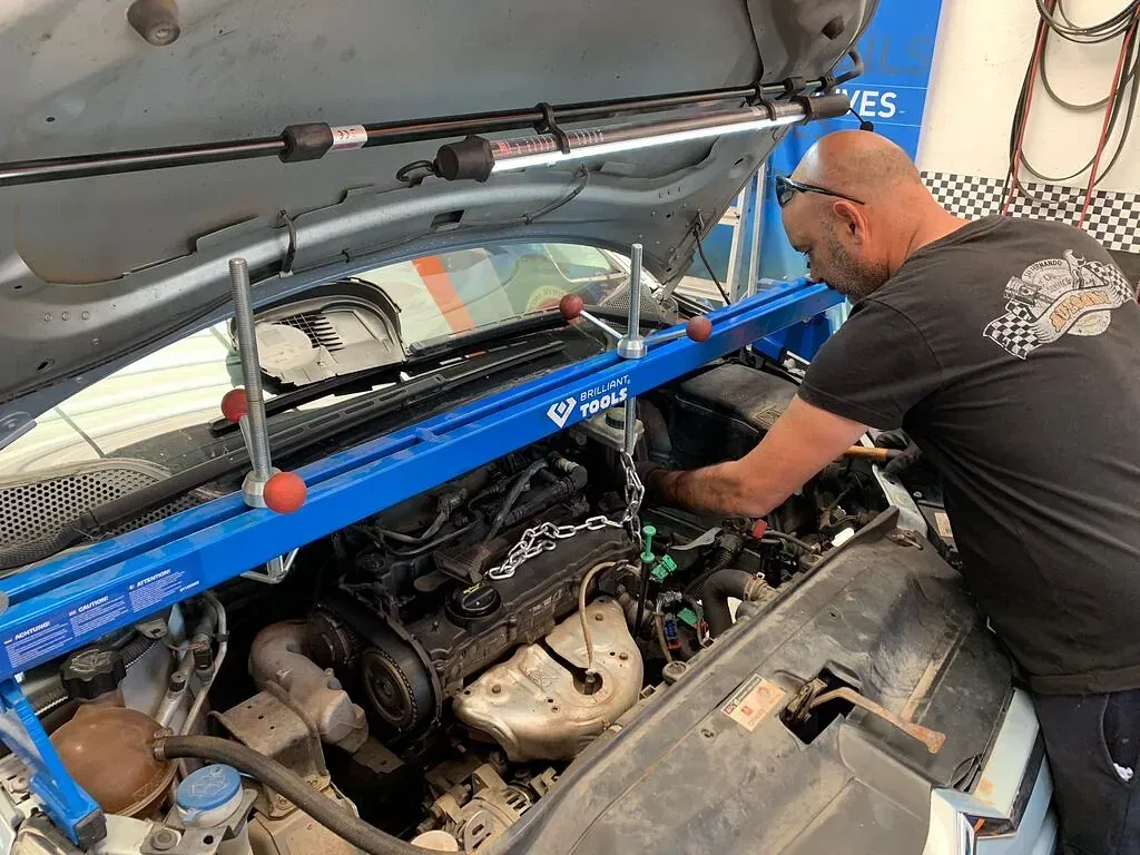 Un hombre está trabajando en el motor de un coche.