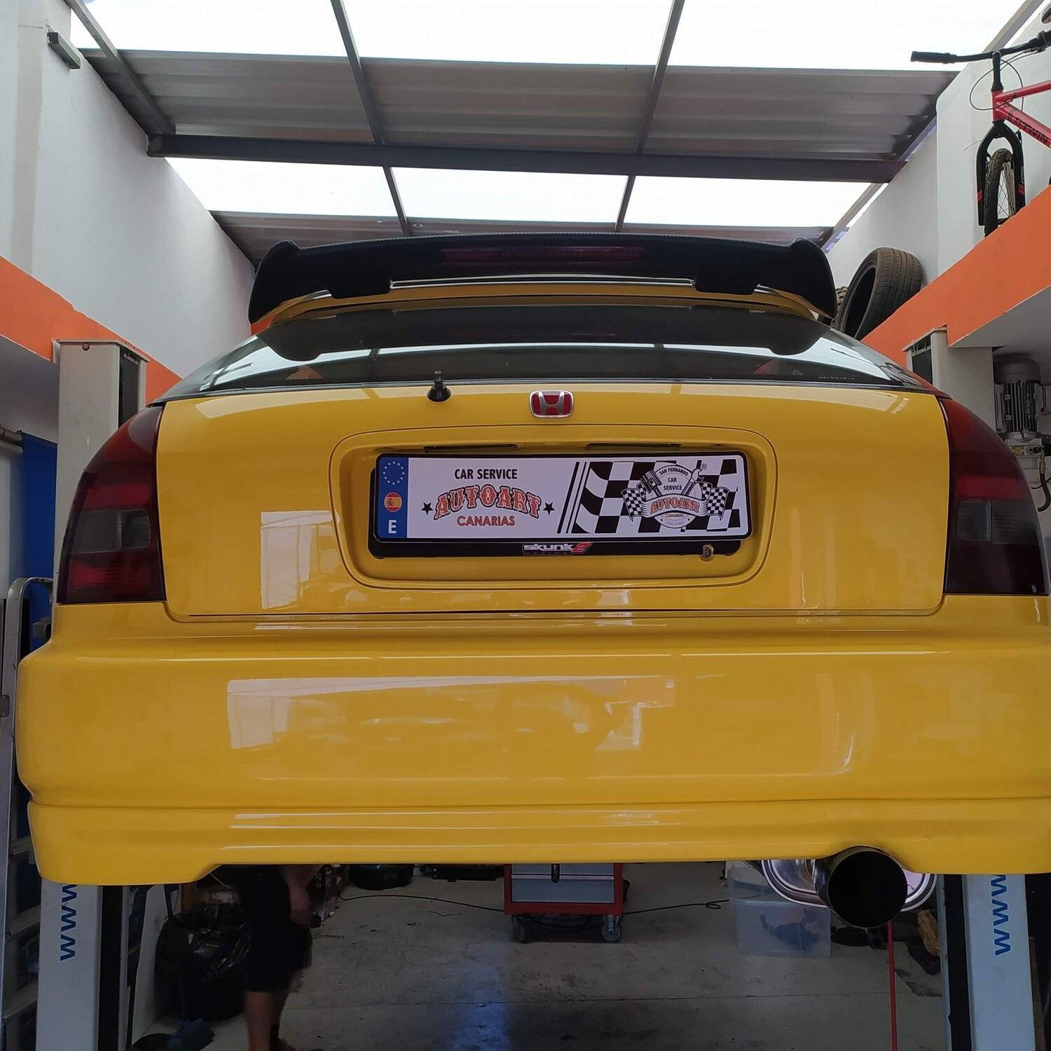 Un coche amarillo está parado en un elevador en un garaje.