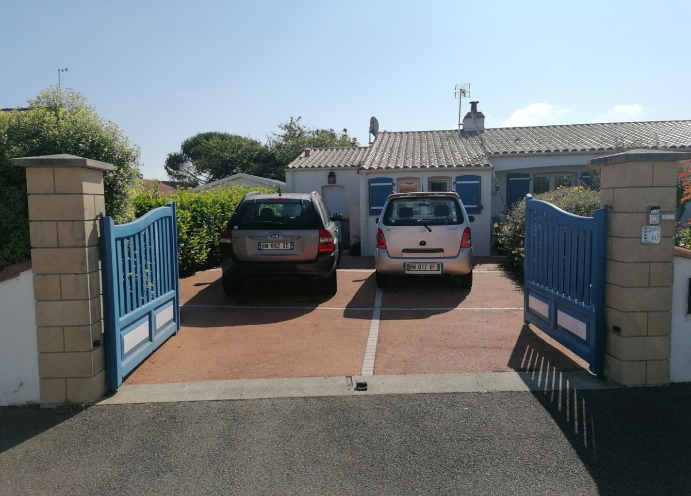 Deux voitures derrière un portail bleu ouvert chez un particulier