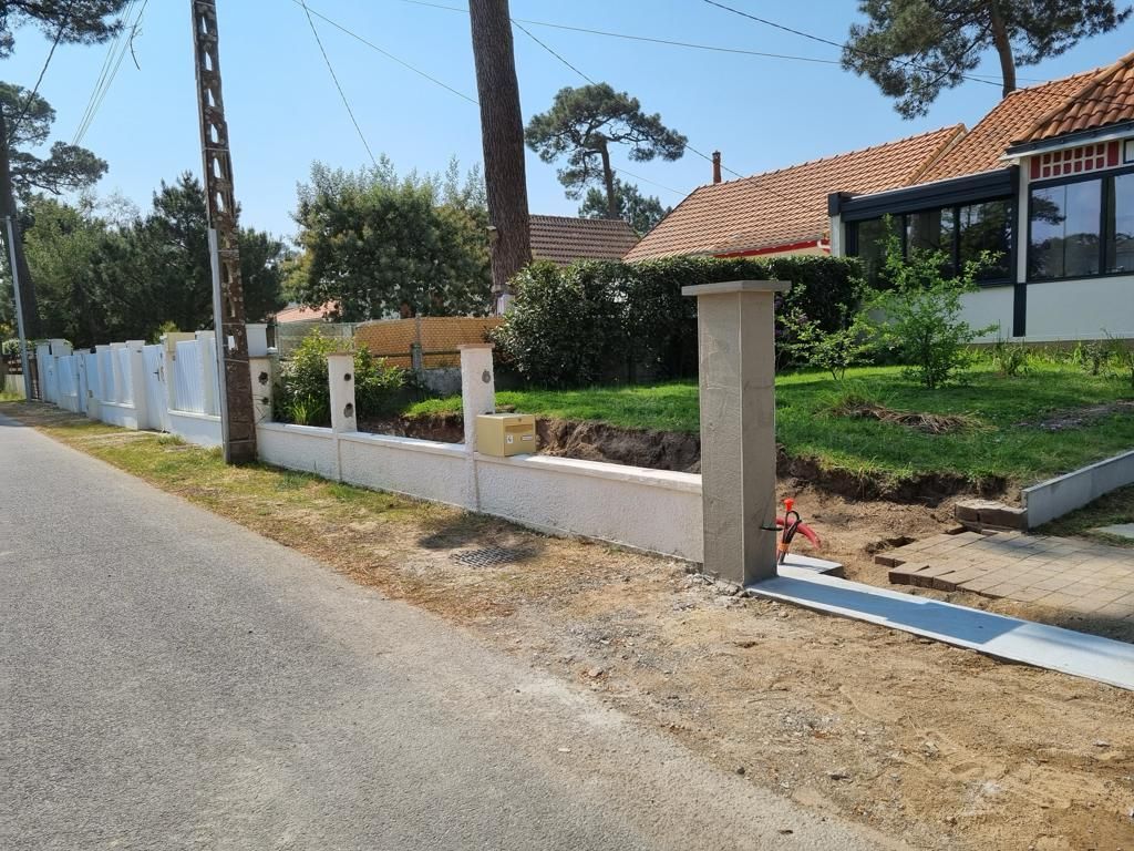 Travaux en cours d'un muret et plusieurs poteaux le long d'une route