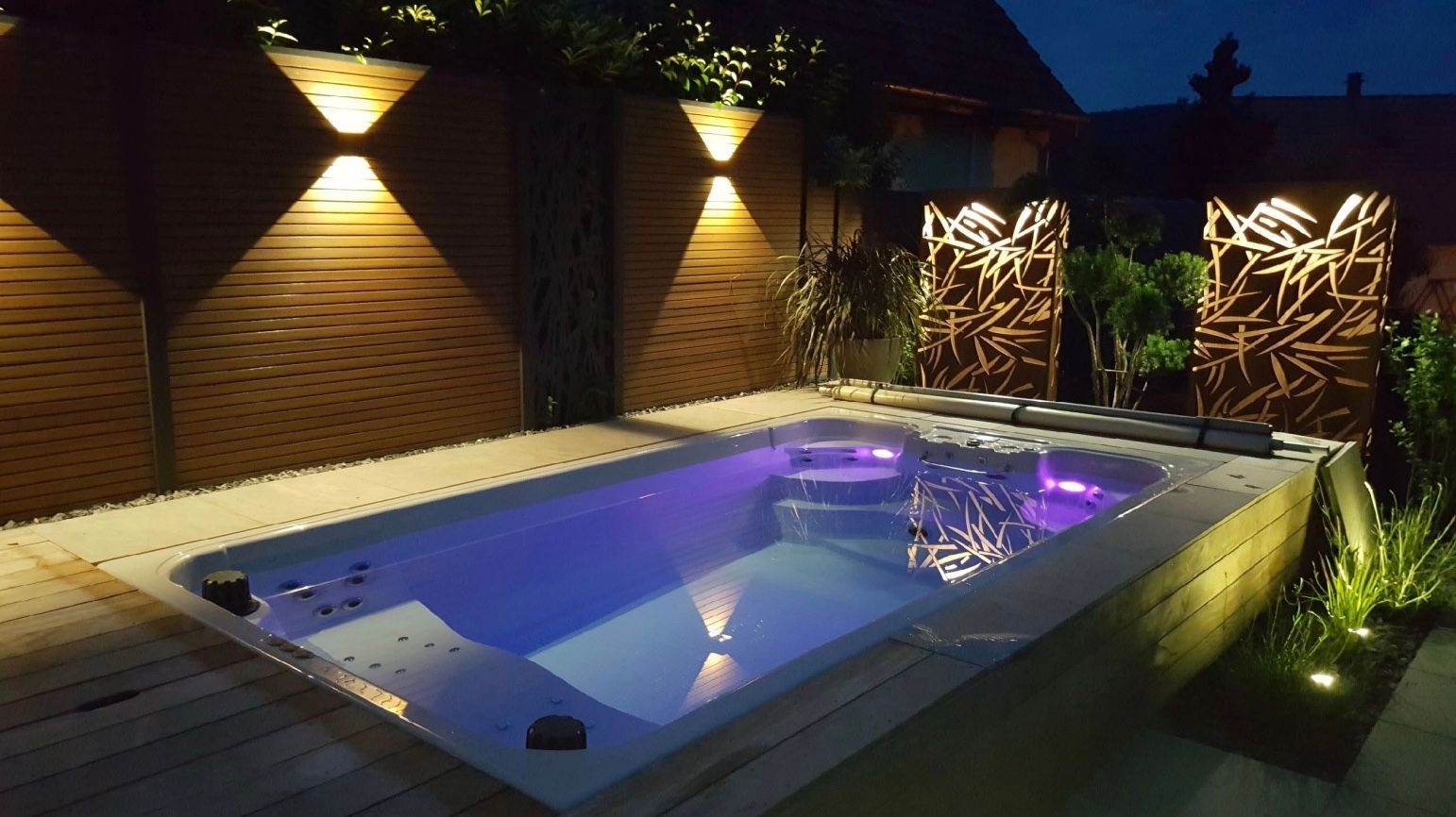 Piscine éclairée de nuit au centre d'une terrasse