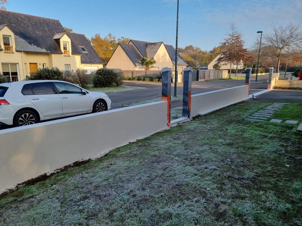 Muret le long d'une propriété avec deux accès délimités par des poteaux