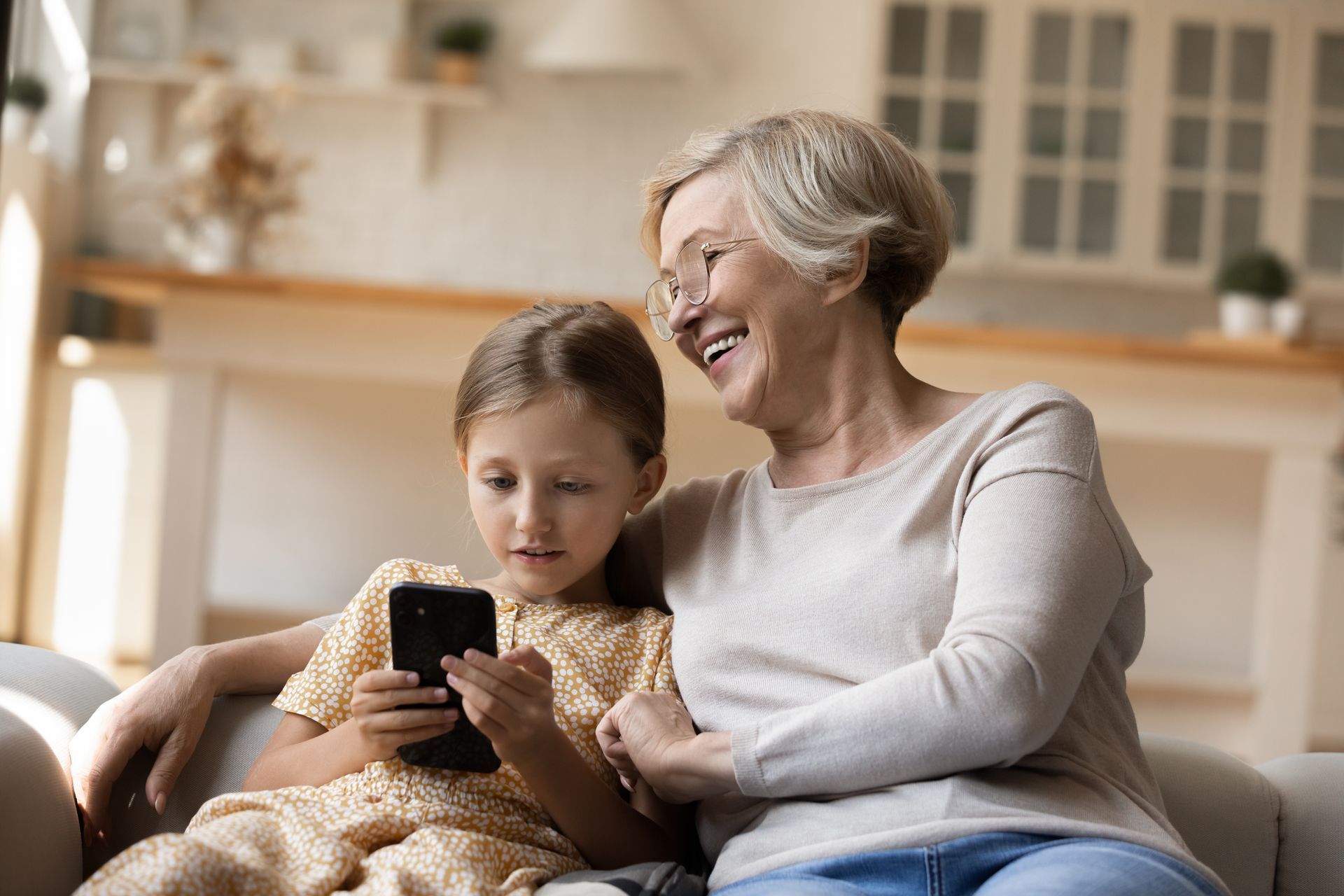 Femme et jeune fille sur un canapé regardent un écran de téléphone