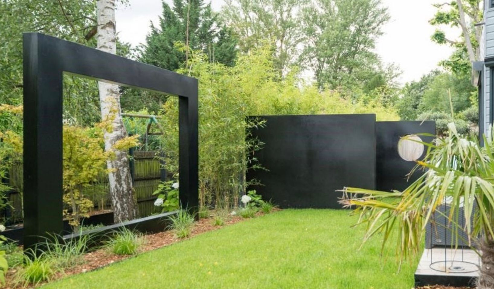 Grands murs noirs design percés  en plein milieu d'un jardin