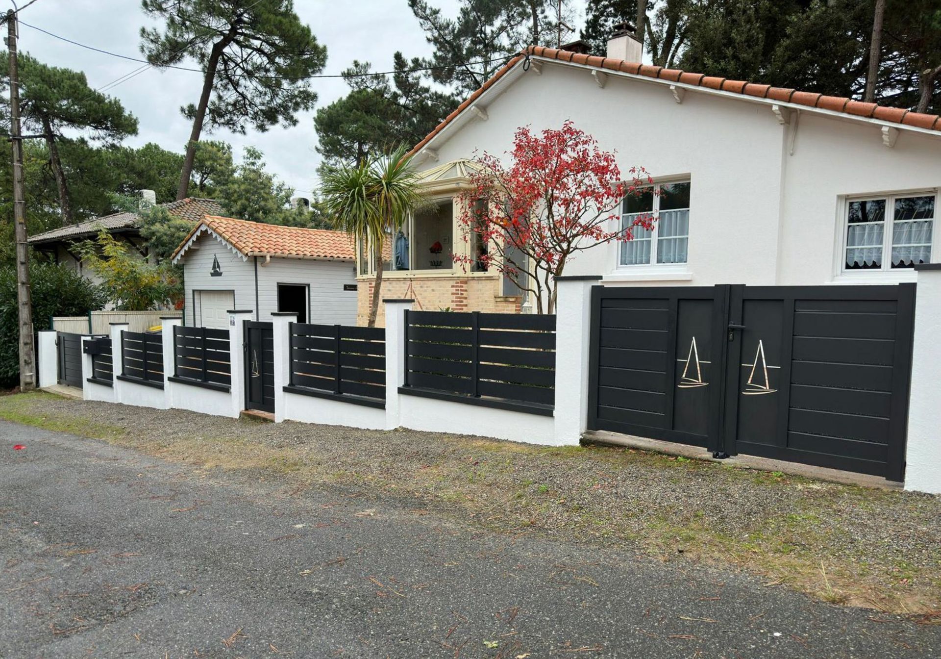Clôture sur muret blanc, porte d'entrée et porte de garage à motifs similaires