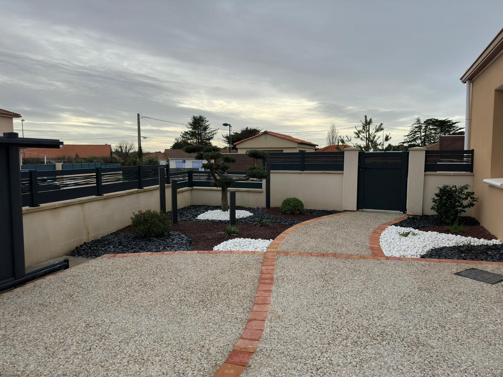 Allée d'une maison avec clôture et portes noires