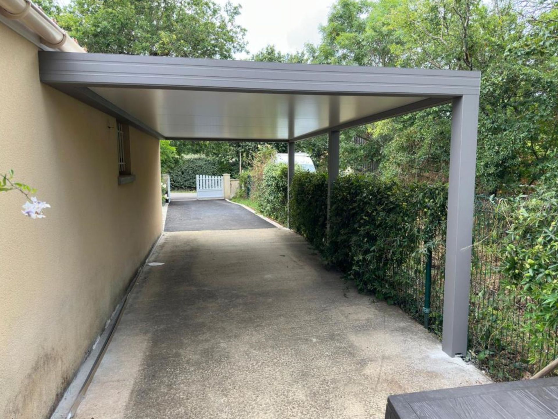 Carport fixé sur un côté de maison avec poteaux déportés