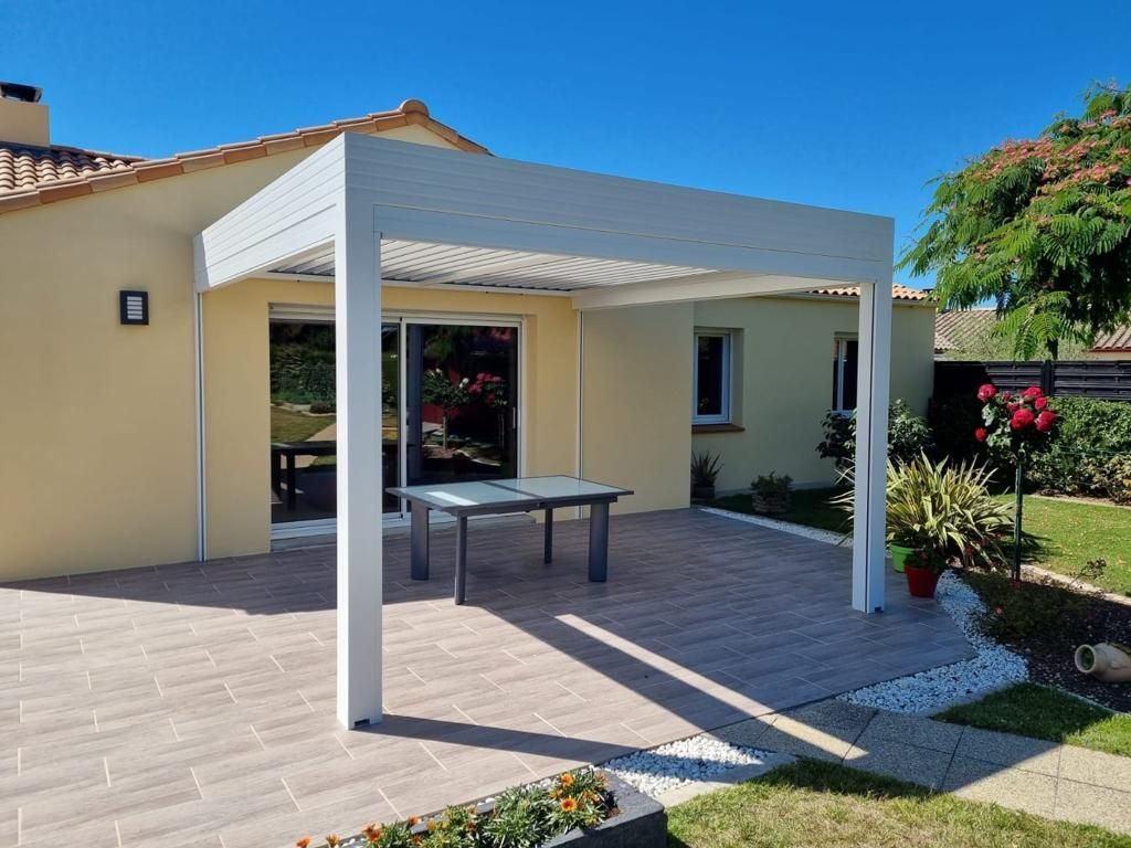 Pergola blanche avec table devant un jardin