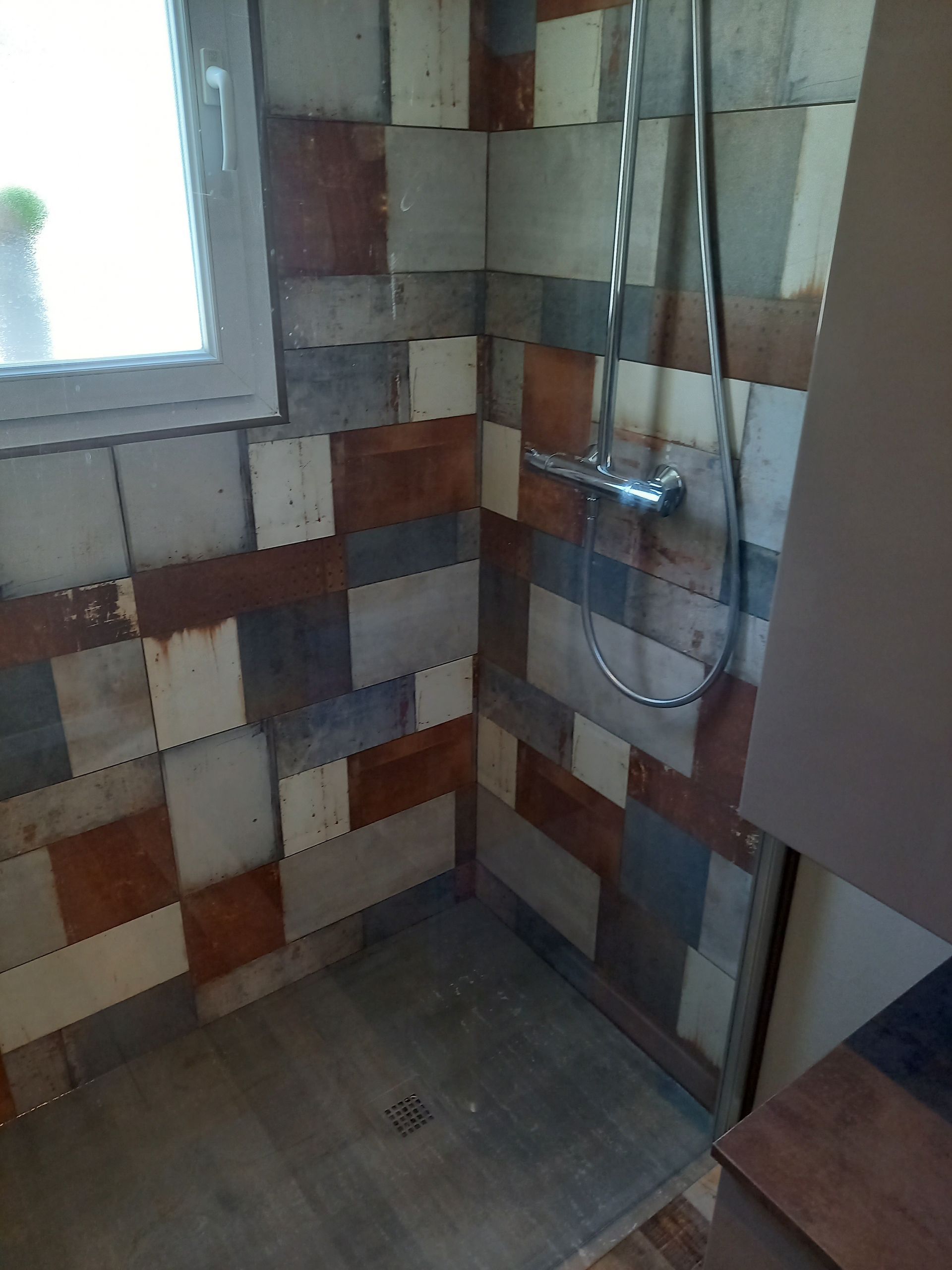 Douche rénovée avec carreaux de faïence gris, bleu et ocre