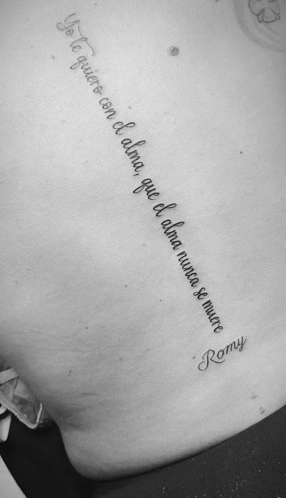 Un tatuaje cursivo en el costado de una persona, fotografiado en blanco y negro.