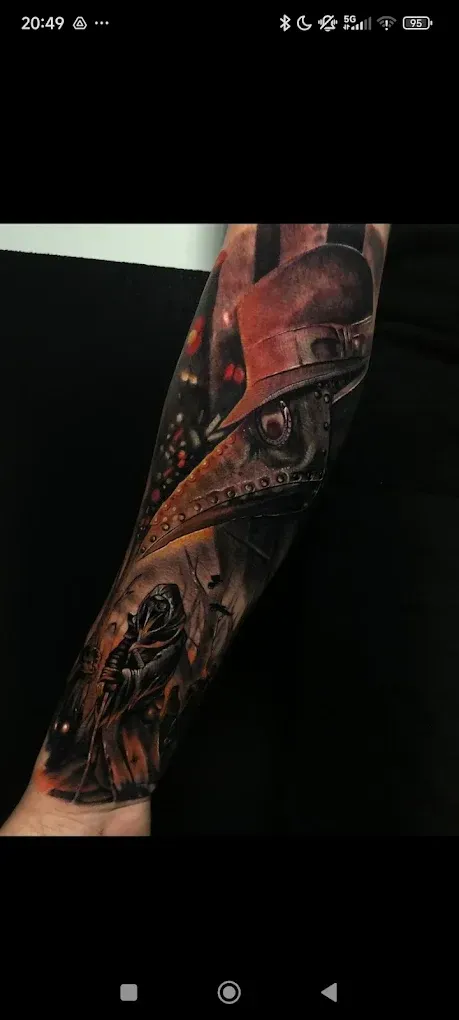 Tatuaje en el antebrazo con una figura encapuchada roja y un diseño gótico oscuro sobre un fondo negro.
