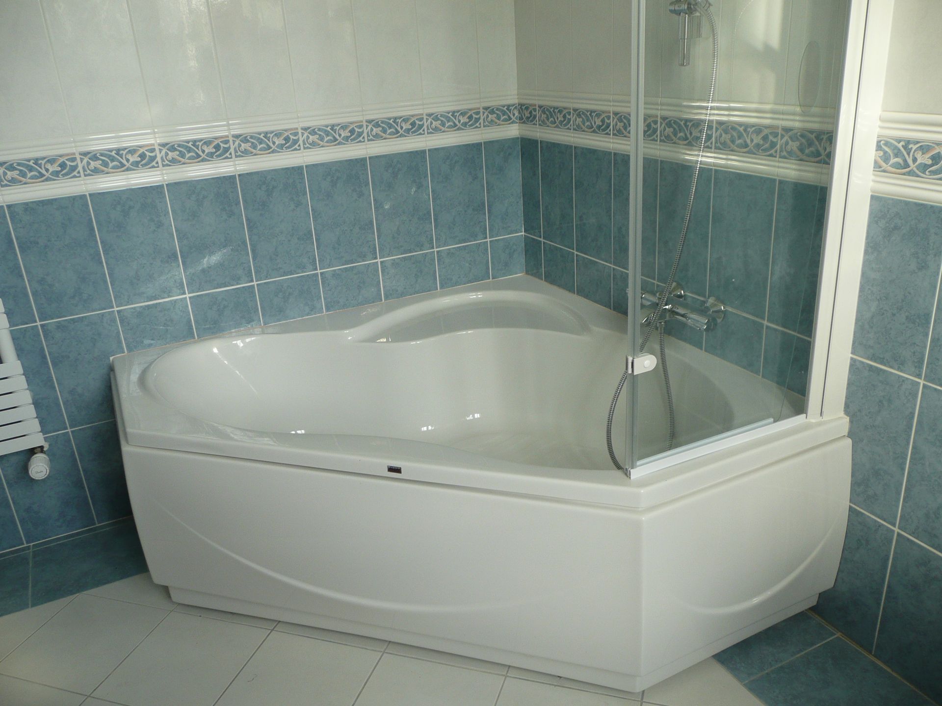 Baignoire en coin dans une salle de bains avec carrelage bleu