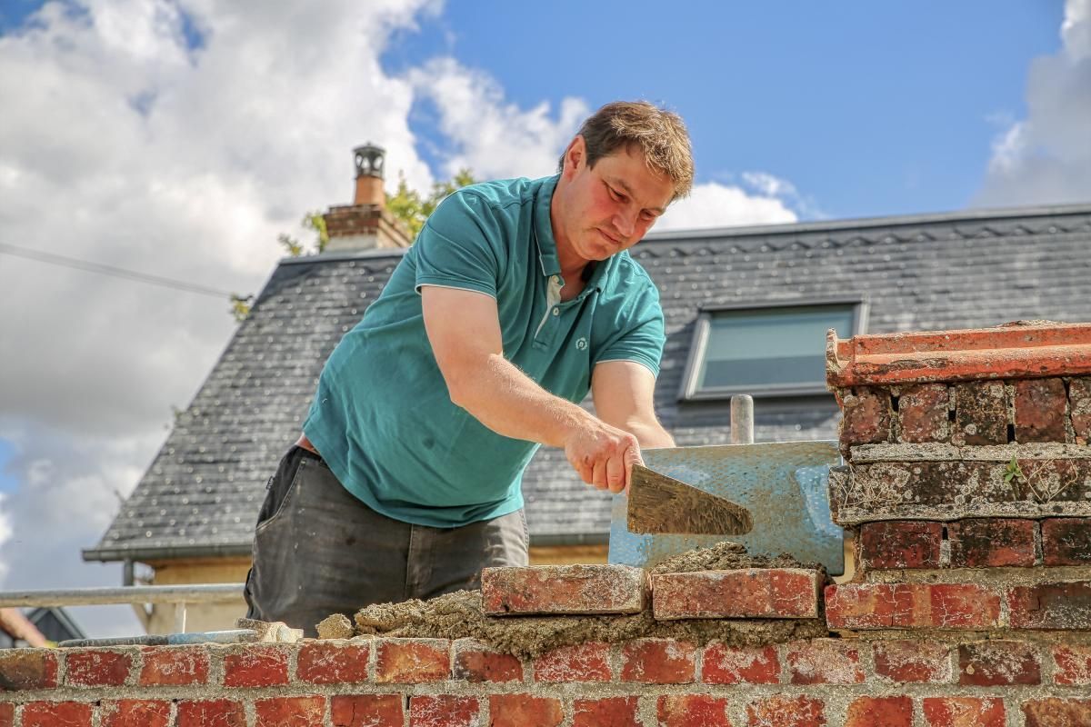 Professionnel construisant un muret de clôture