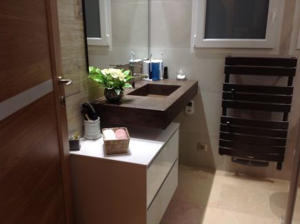 Un lavabo installé en face d’un miroir et un sèche-serviettes