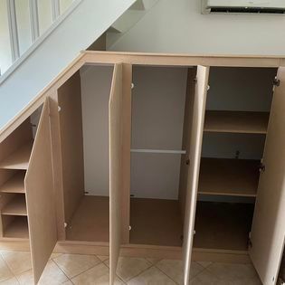 Un placard ouvert installé sous des escaliers