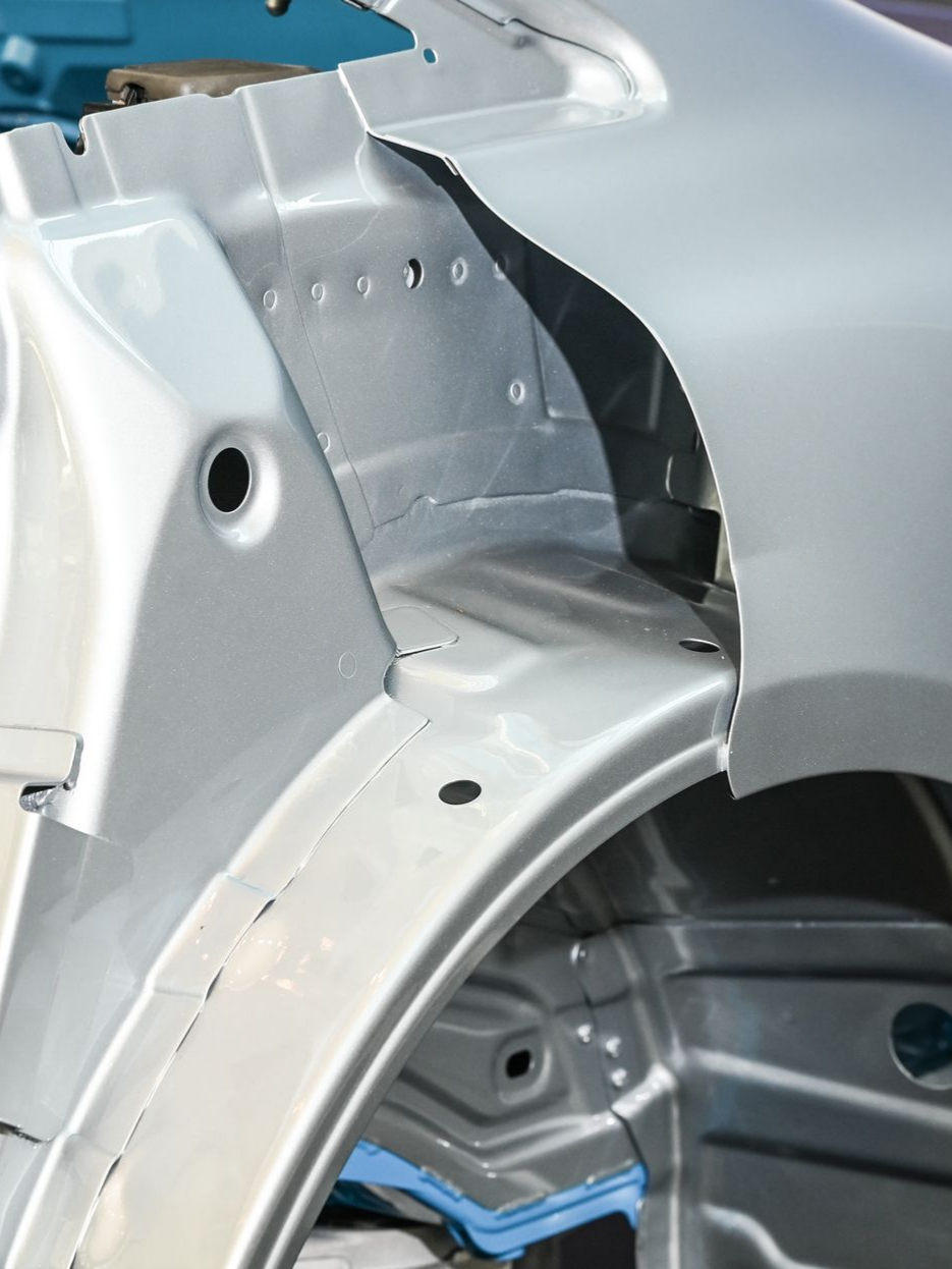 Châssis de voiture argenté montrant le passage de roue et les supports structurels internes.