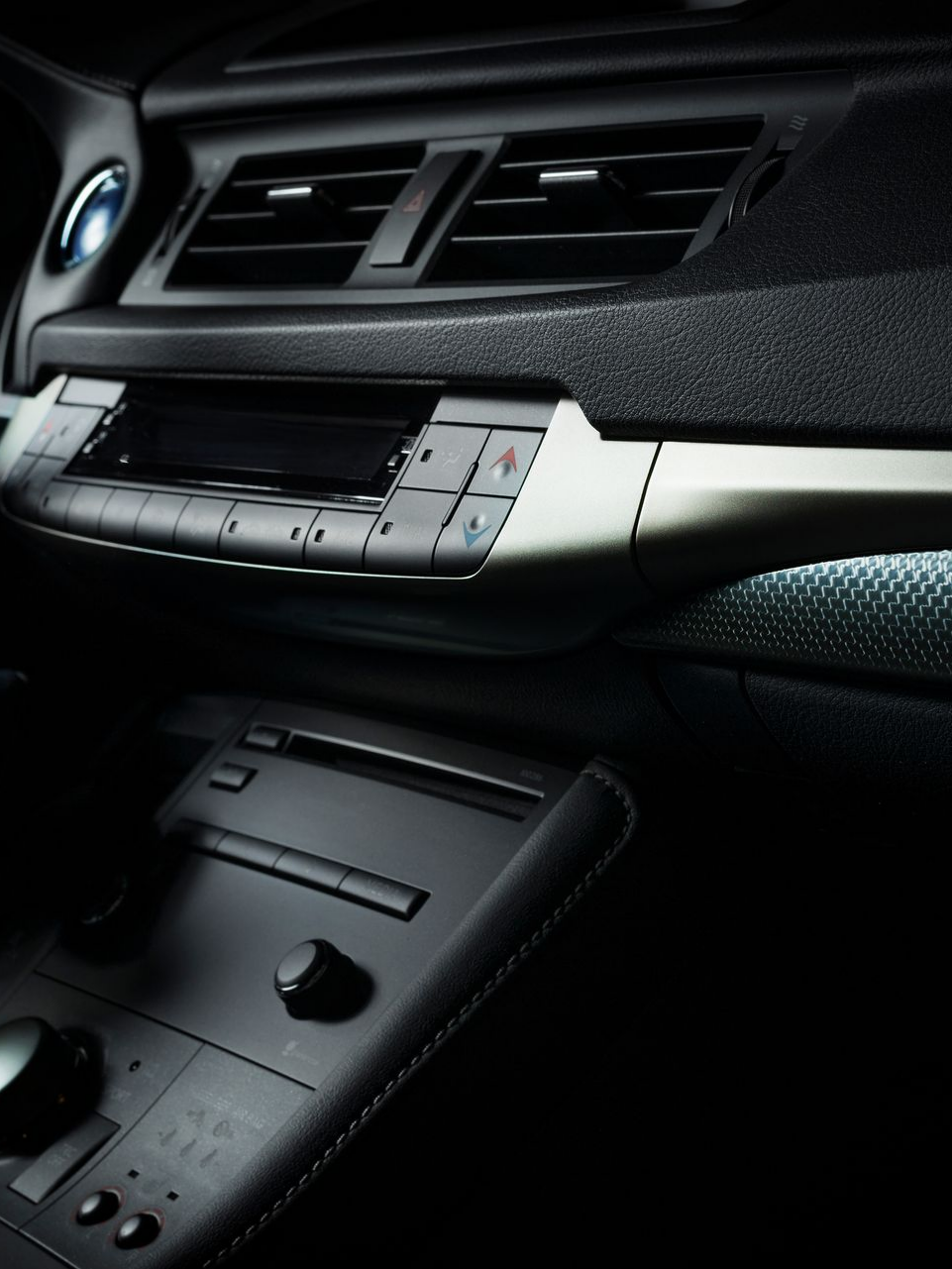 Intérieur de la voiture : tableau de bord avec aérateurs, console centrale avec boutons et garnitures métalliques.