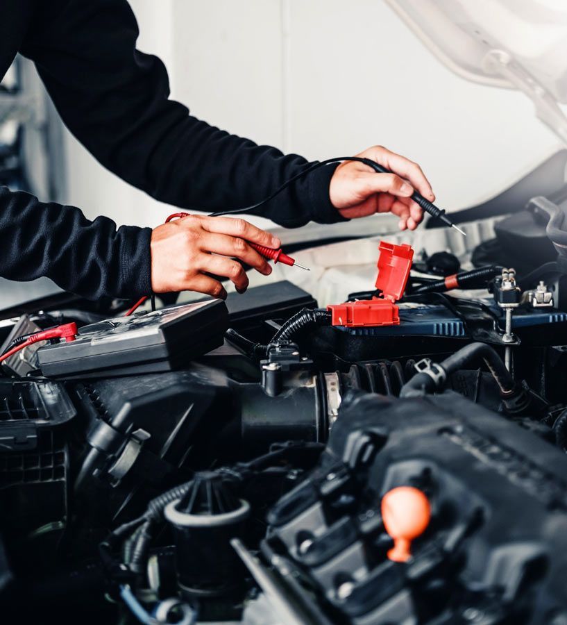 Mecánico usando un multímetro para inspeccionar el motor de un automóvil.