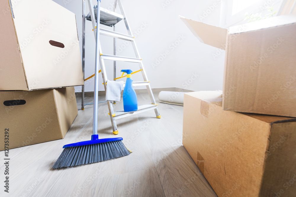 Umzugskartons, Leiter, Wischmopp und Kehrschaufel in einem hellen Raum beim Putzen oder Auspacken