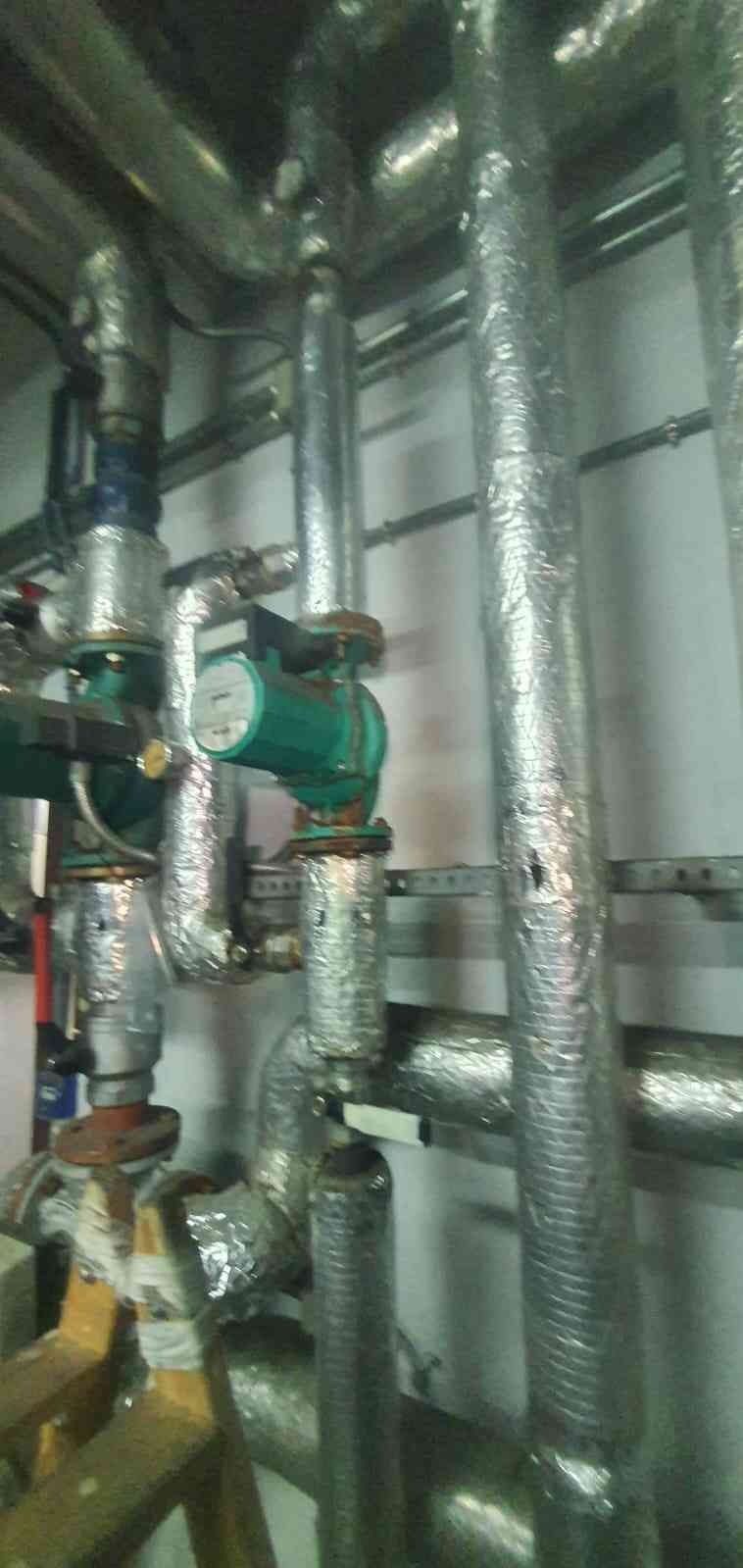 Tuberías con aislamiento y válvulas en un entorno industrial. Parte del aislamiento está dañado.