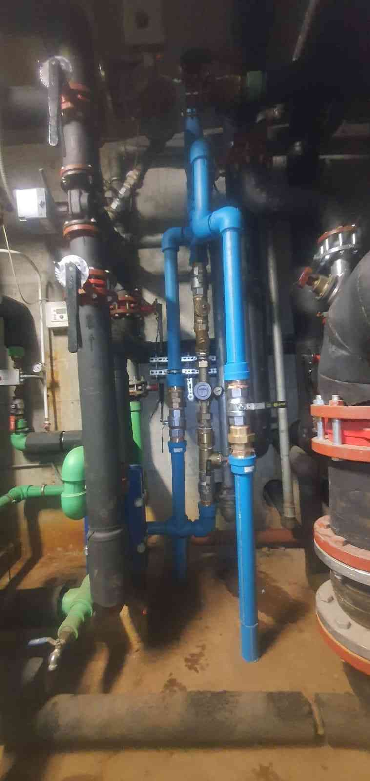 Tuberías azules y negras con varias válvulas y accesorios en una sala de máquinas.