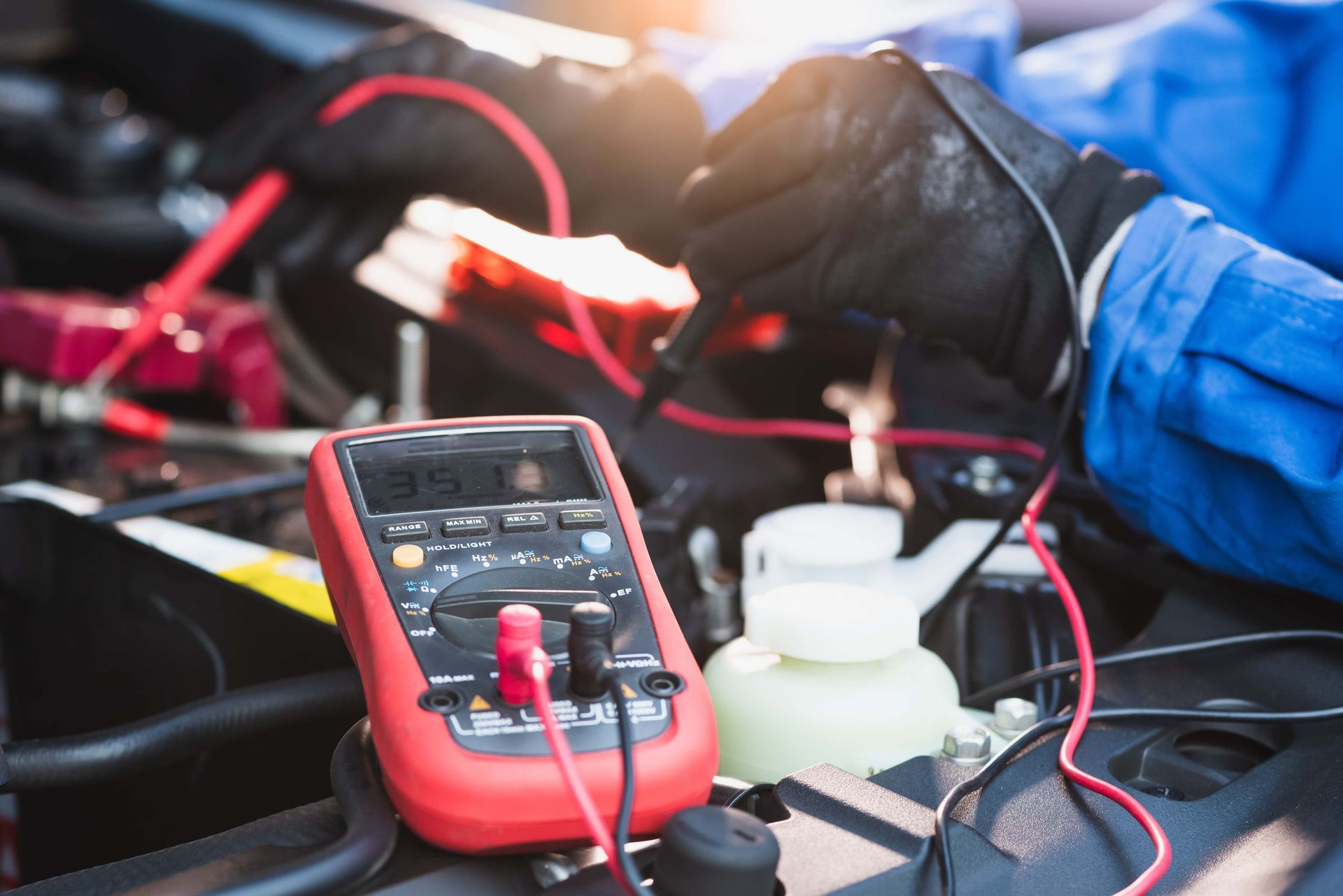 Une personne utilise un multimètre pour tester une batterie de voiture.