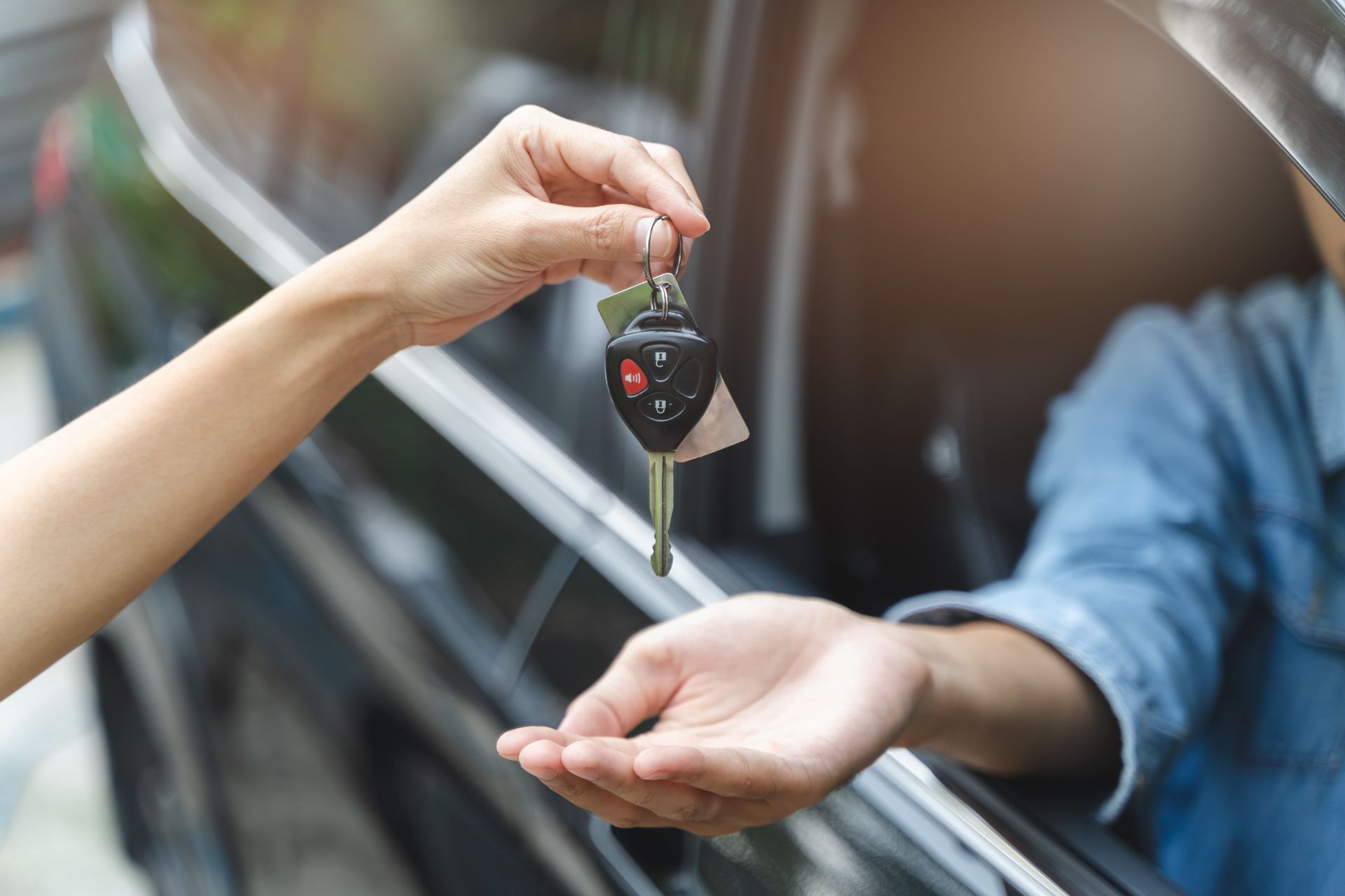 Une personne donne une clé de voiture à une autre personne.