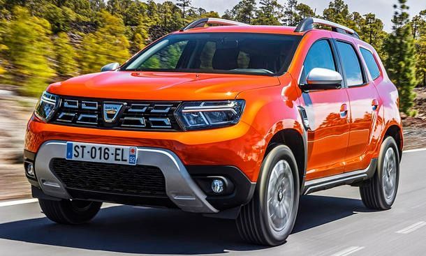 Une voiture rouge roule sur une route à côté d'arbres.