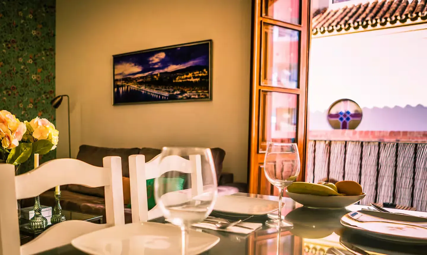 Comedor con mesa puesta para comer; ventana con vidrieras, pintura en la pared.