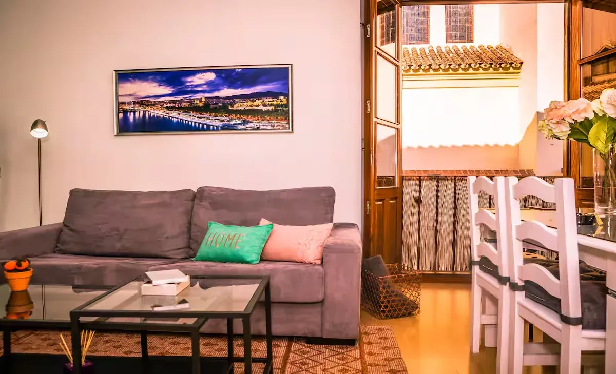 Sala de estar con sofá morado, mesa de cristal y mesa de comedor.