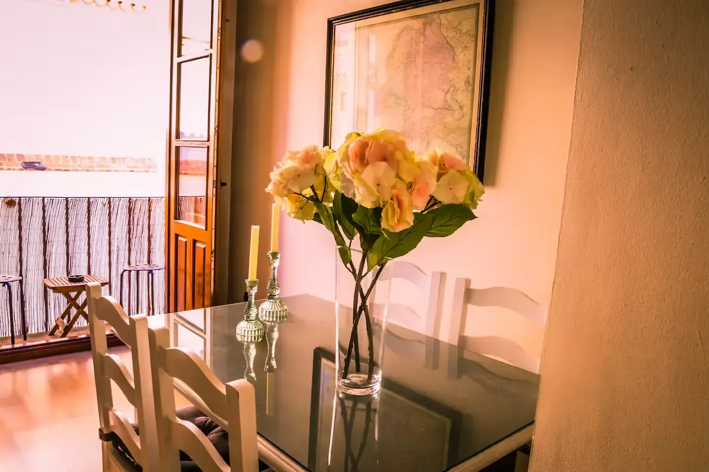 Mesa de comedor con flores y vista al balcón.